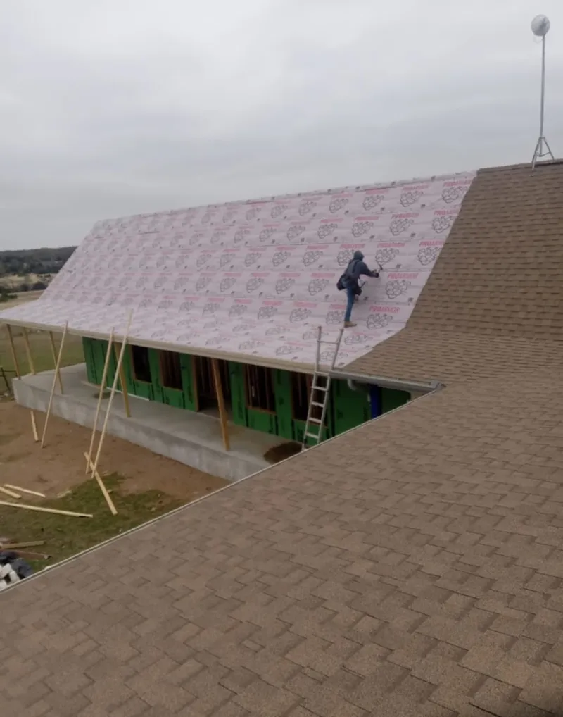 Worker preparing underlayment for a metal roof installation in Federal Heights